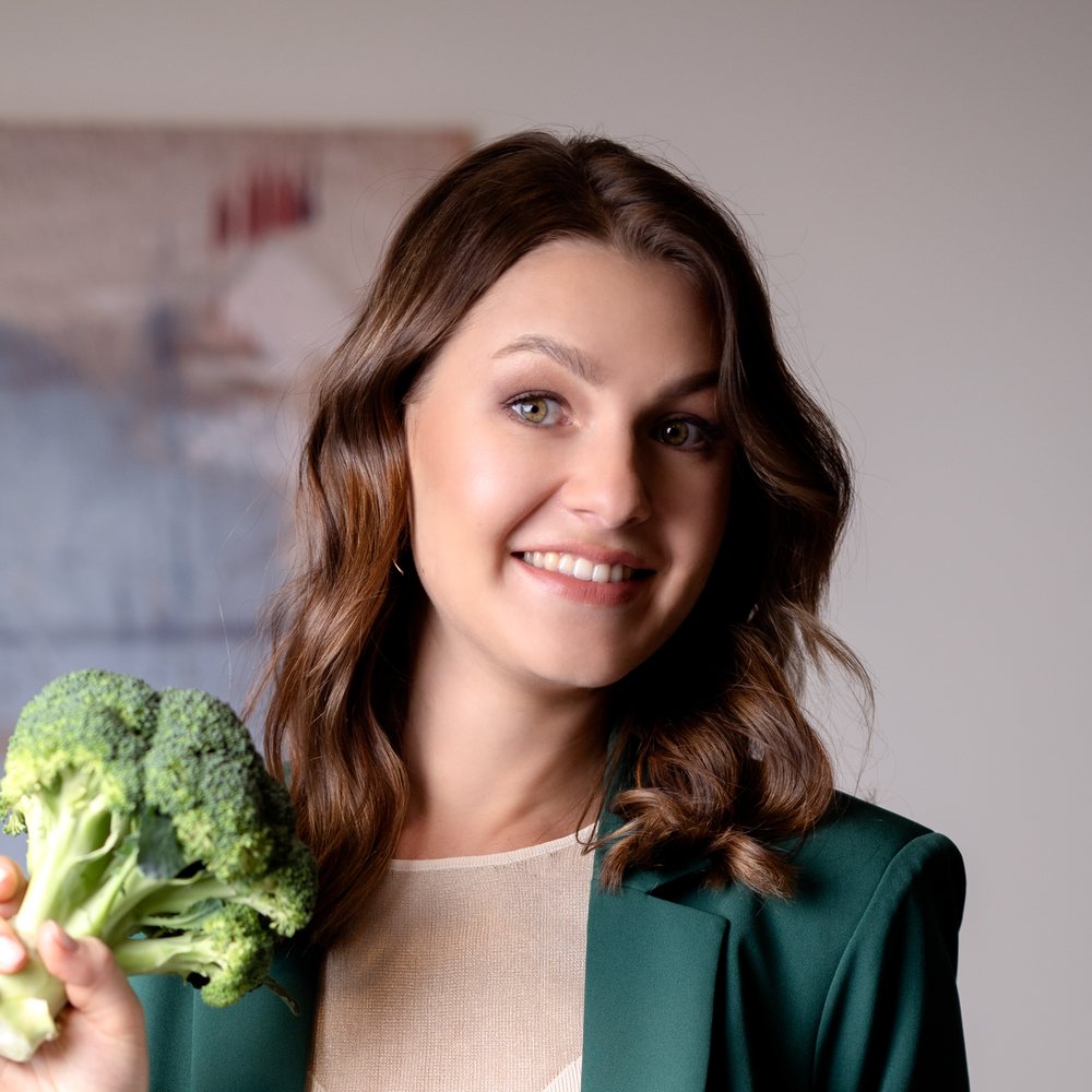 Natalia, smiling, holding broccoli