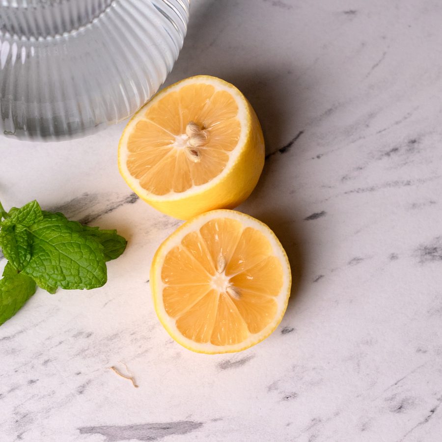 Lemon slices and mint beside a glass carafe of water